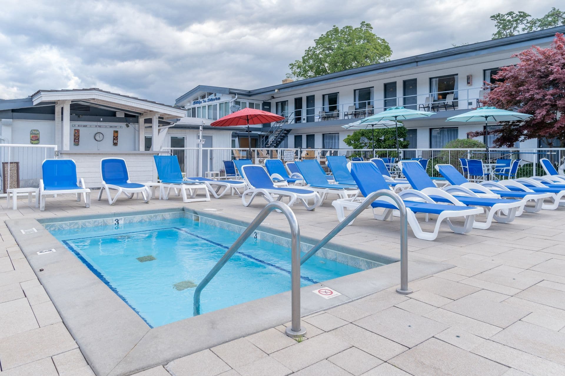Outdoor pool and blue lounge chairs at Ship-n-Shore Hotel